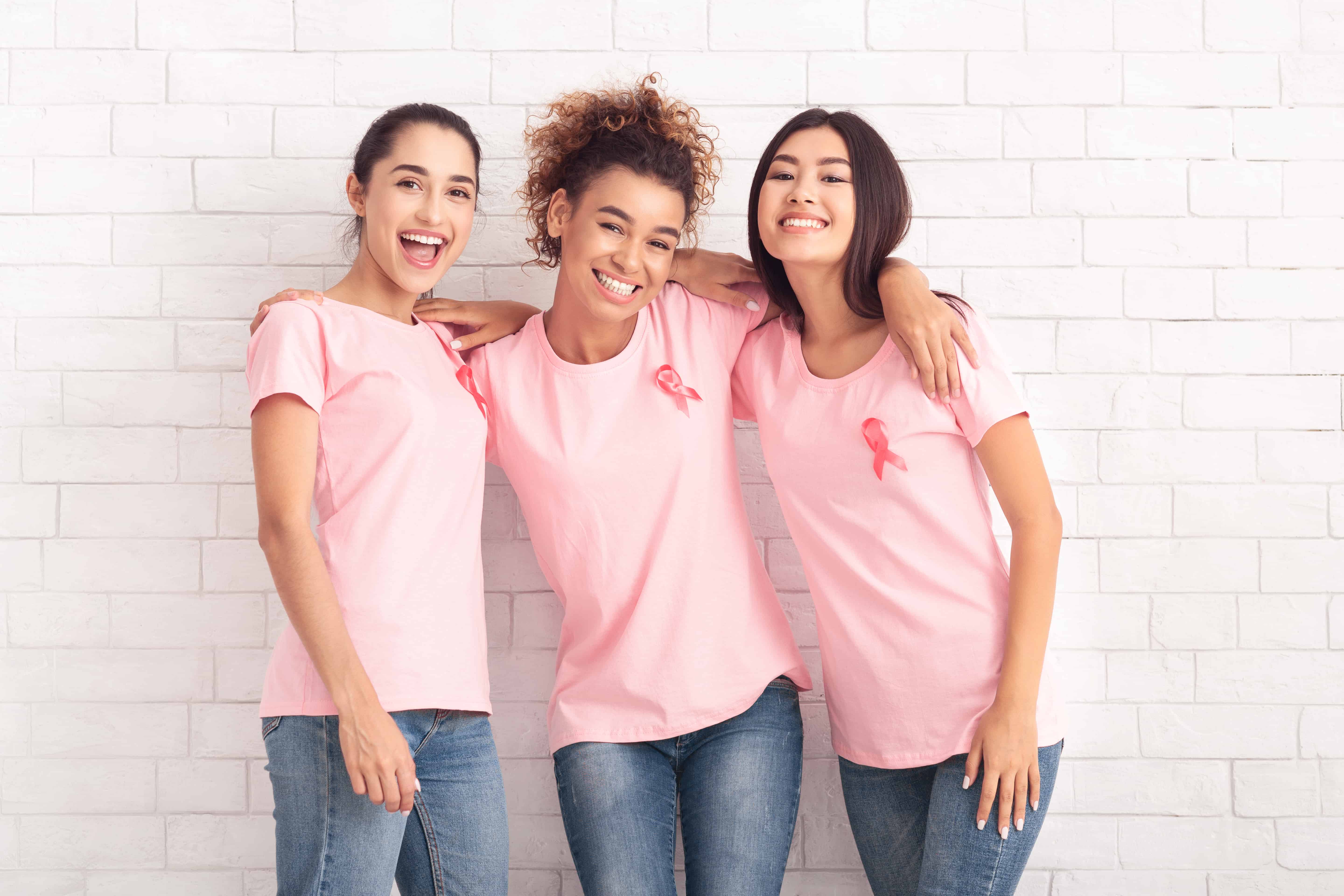 Three women wearing pink ribbons